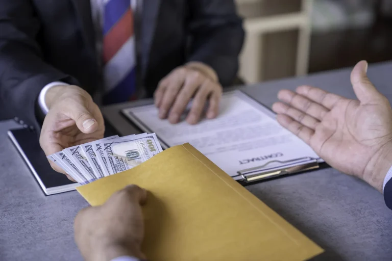 Businessmen shaking hands and exchanging money after signing paperwork, symbolizing a surplus funds recovery payout.