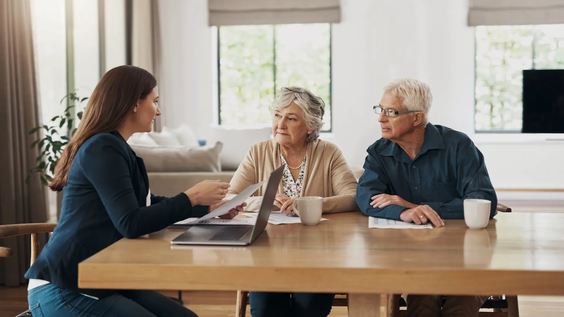 Housing consultation helping an older couple review property paperwork and residential options.