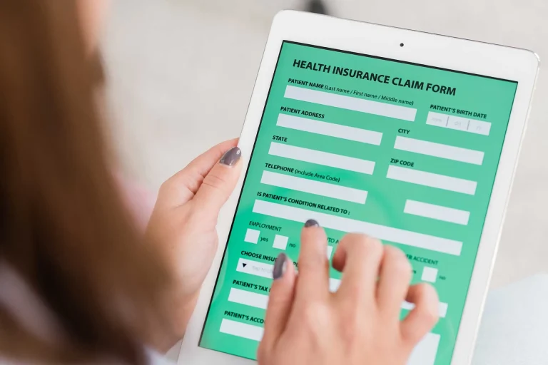 Person completing a health insurance claim form on a tablet for medical coverage and healthcare service reimbursement.